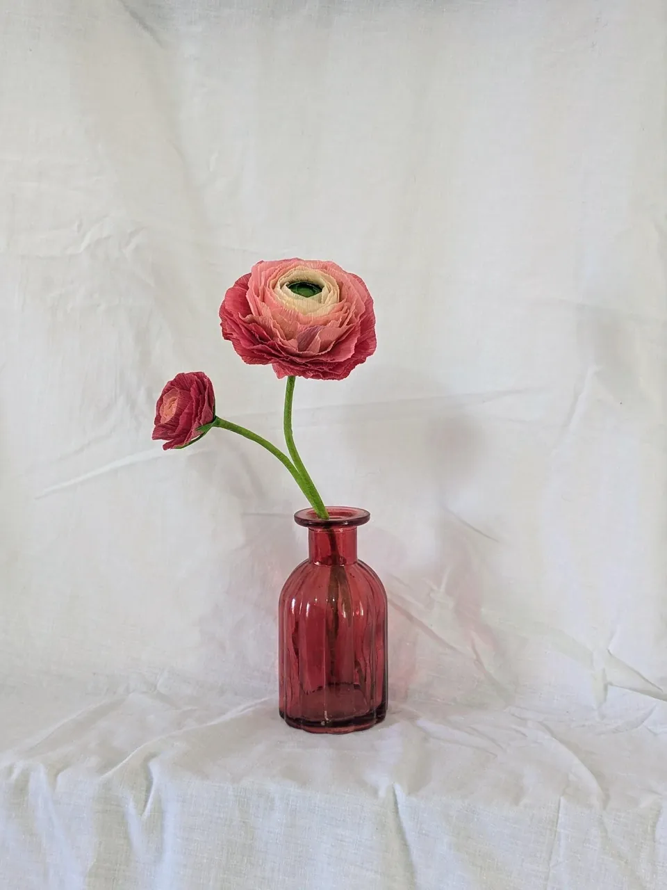 Renoncule rose en papier dans un vase rouge